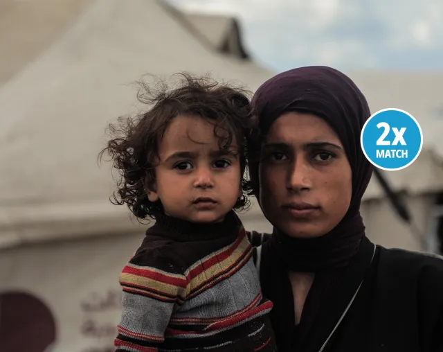 Woman holding a young child at a displacement camp in Gaza.