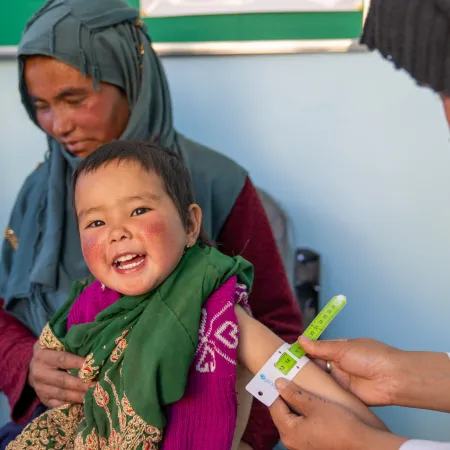 A girl smiles while getting the arm circumference measured for malnutrition. 