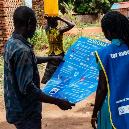 Community staffers inspect a COVID-19 education poster.