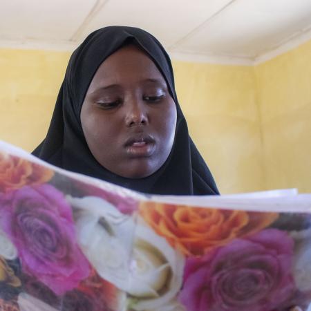 A girl looks down at a notebook while sitting at her desk.