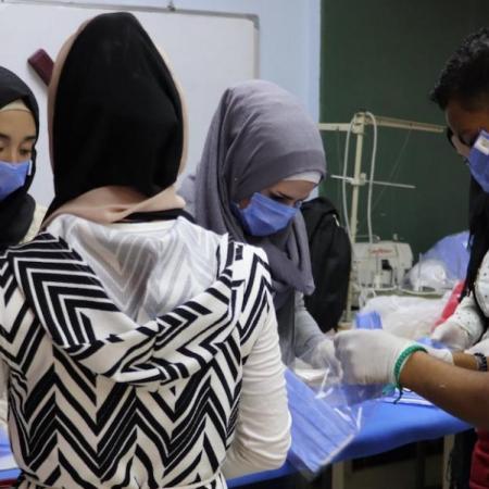 Syrian youths work to make cloth masks.