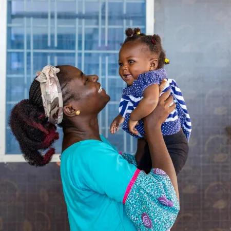 A woman holds up a smiling baby.