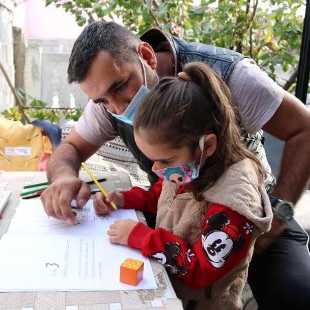 Hazir helps his daughter Naida study.