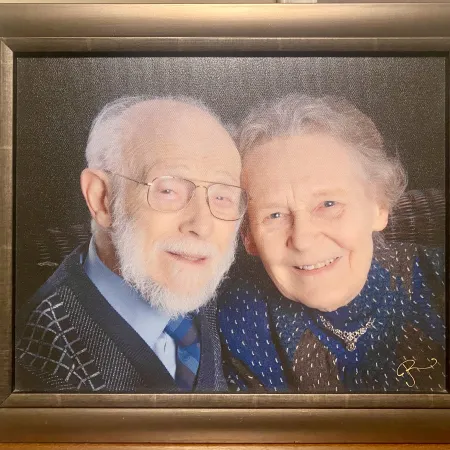 A photo of a framed photo of an elderly couple looking at the camera smiling with their heads touching. 
