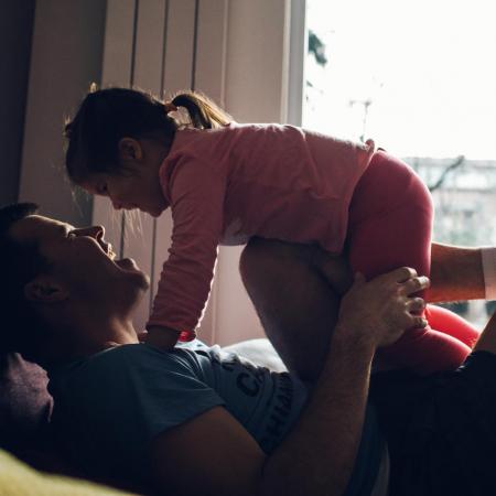 Father playfully lifting his daughter in the air
