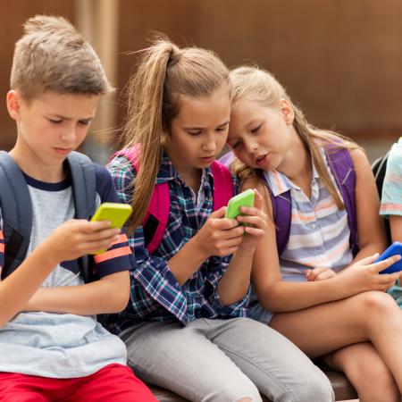 A group of children look at their phones.