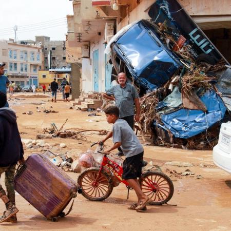 Un garçon tirant une valise marche parmi les débris dans un quartier de Derna endommagé par une crue éclair, en Libye.