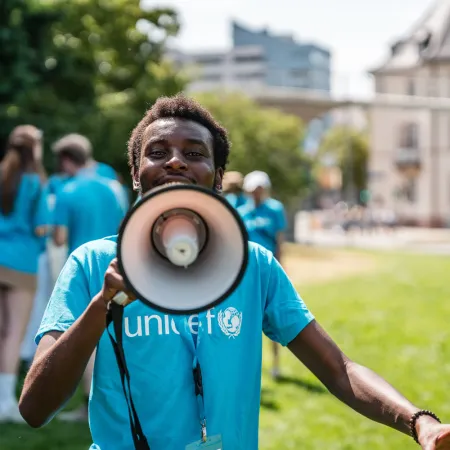 Des jeunes portant un t-shirt de l'UNICEF parlent dans un mégaphone