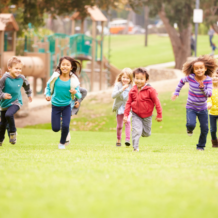 Sept enfants courent vers la caméra dans une cour de récréation.