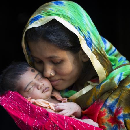 A Bangladeshi mother holds her newborn daughter up to her face.