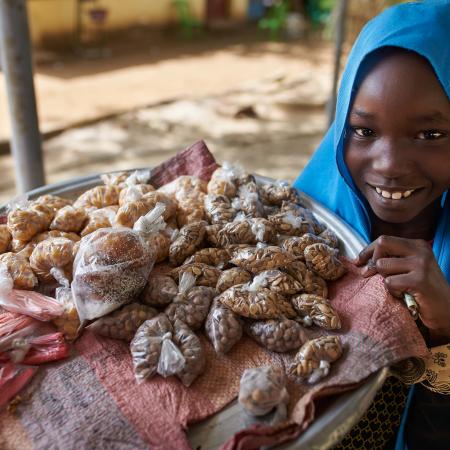 Girl smiling beside small plastic bags of food