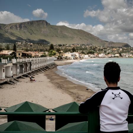 A boy who is an unaccompanied minor looks across the beach in Trabia, Italy, on May 14, 2016. 