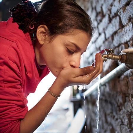 A girl drinks clean water from a tap.
