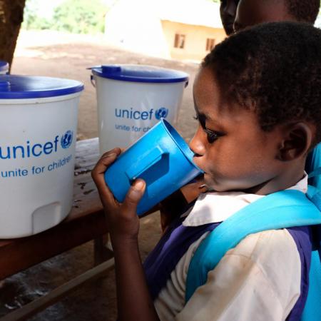 A student drinks from a cup with a UNICEF logo.