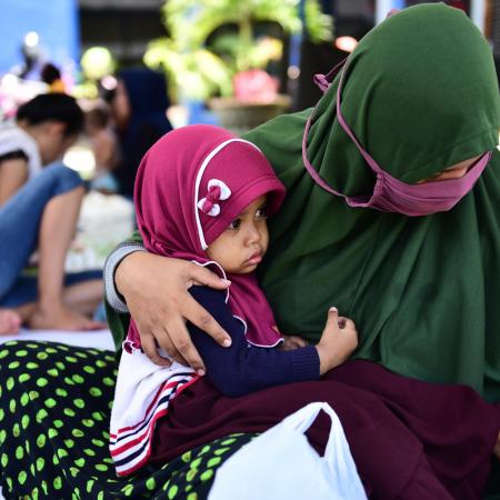 A baby sits in her mother's lap at a temporary shelter in Palu in 2018.