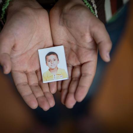 A Syrian boy holds a photo of himself in kindergarten.