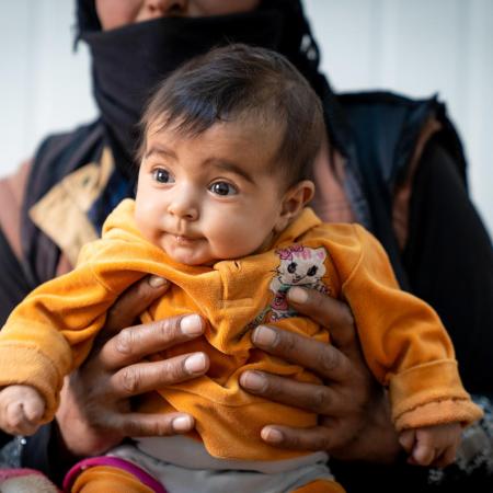 A baby waits to receive new winter clothes in Zaatari Refugee Camp, Jordan.