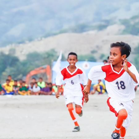 Two boys take part in a soccer match.