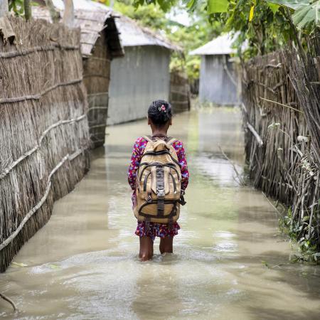  Child wades through water on her way to school in Bangladesh