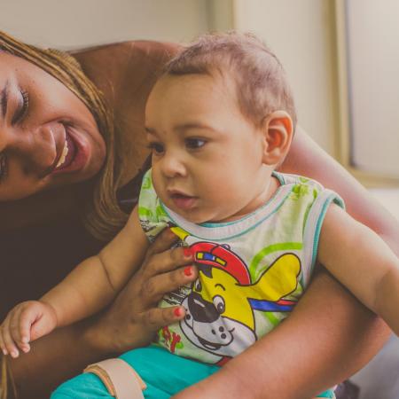 A mother plays with her young baby