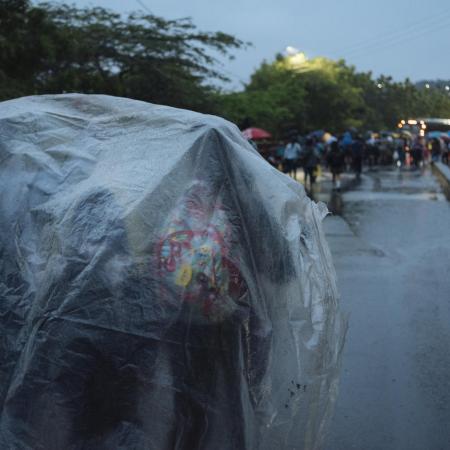 Children shelter under a plastic tarp while waiting to cross the border from Venezuela.