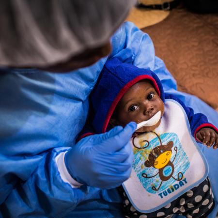 Christ-Vie, an Ebola orphan, is fed by a caretaker in Butembo.