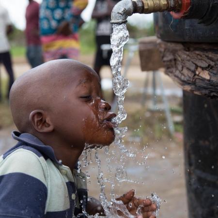 A child drinks from a water point at the Samora Machel II accommodation centre.