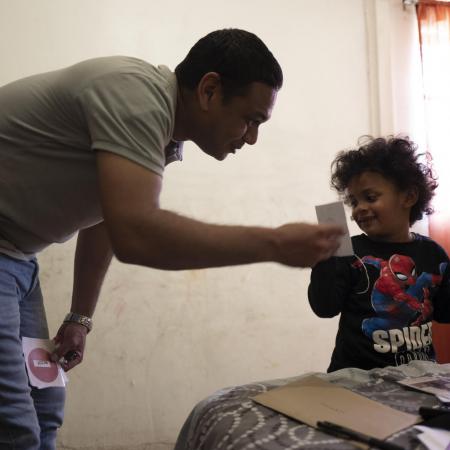 A father helps his son brush his teeth.