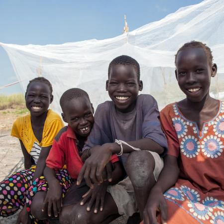 Friends sit by a UNICEF-supplied mosquito net in Bienythiang in Akoka county, Upper Nile state, South Sudan.