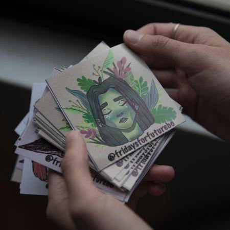 A girl holds stickers with the hashtag Fridays for Future printed on them.