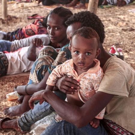 An Ethiopian refugee child who fled fighting in Tigray province sits holding a child in a hut at the Um Raquba camp in Sudan's eastern Gedaref province, on 16 November 2020. Sudan – one of the world's poorest countries, now faced with the massive influx – has reopened the camp, 80 kilometres (50 miles) from the border. It once housed refugees who fled Ethiopia's 1983-85 famine that killed over a million people.