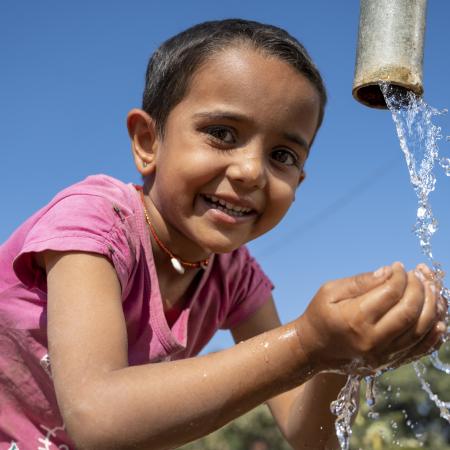 Jhanu (5 yrs) drinks water from the village hand pump near her anganwadi. 