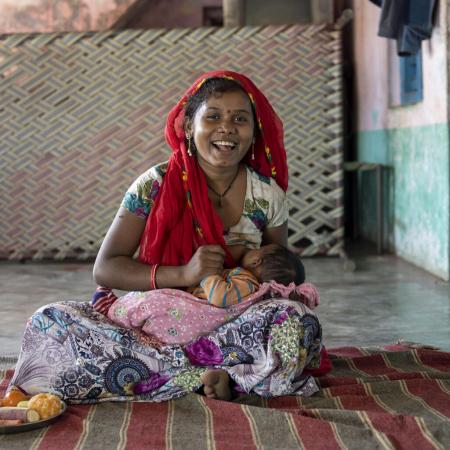 A young mother breastfeeds her newborn baby at a tea estate in India.