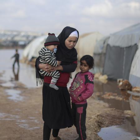 On 19 January 2021, families stand outside of tents in a flooded area of Kafr Losin Camp in northwest Syrian Arab Republic.