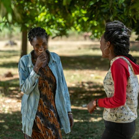 A woman and her daughter talk outside their home.