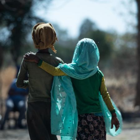 Two girls walk down a road in Ethiopia.