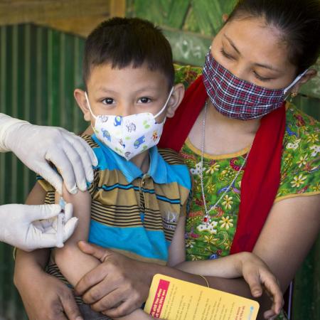 A child sits on his mother's lap as he receives an MMR vaccine.