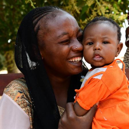 A mother smiles as she hugs her baby.