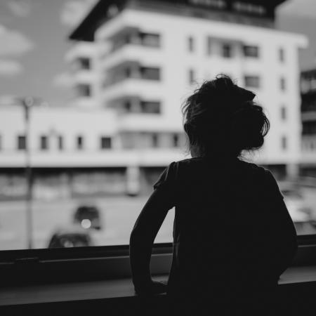 La petite fille de trois ans, Lana, regarde par la fenêtre son jardin d'enfants