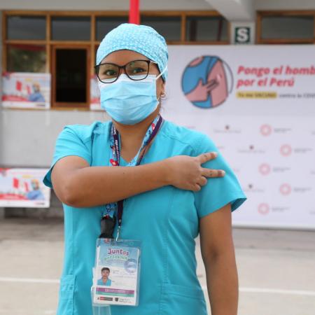 A health worker gives the V for Vaccinated sign after receiving their first COVID-19 vaccine in Peru.