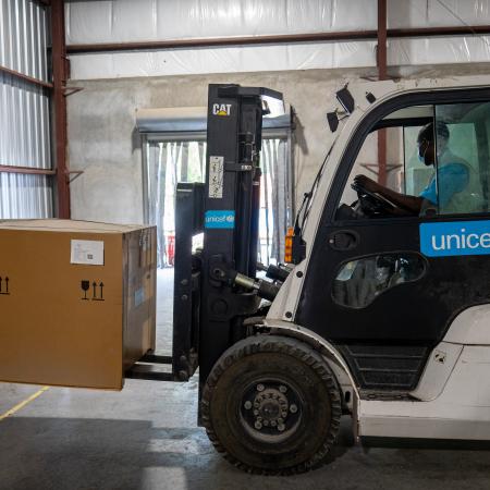 UNICEF Haiti supply officer Jeremie Thomas fork-lifts a solar fridge in the warehouse in Port-au-Prince.