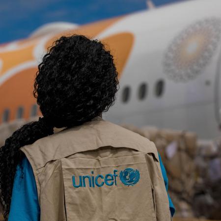 A UNICEF staff member watches as COVID-19 vaccines are unloaded from a plane.