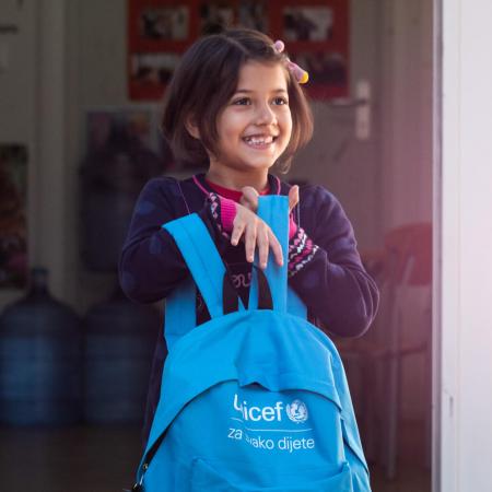 A young girl holds her UNICEF-supplied backpack.