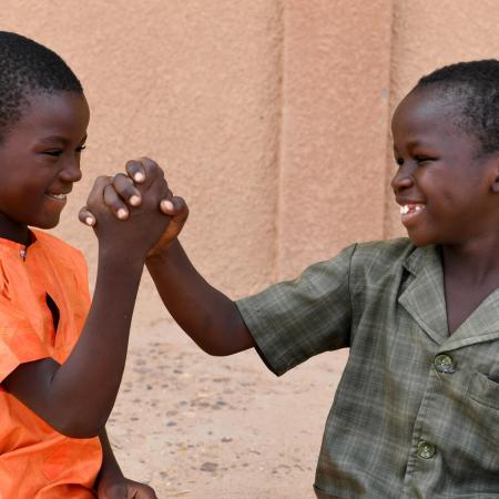 Two boys hold hands outside a school in Niger