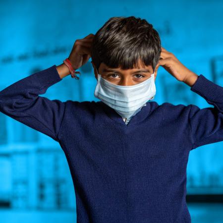 Young boy in blue wearing a facemask
