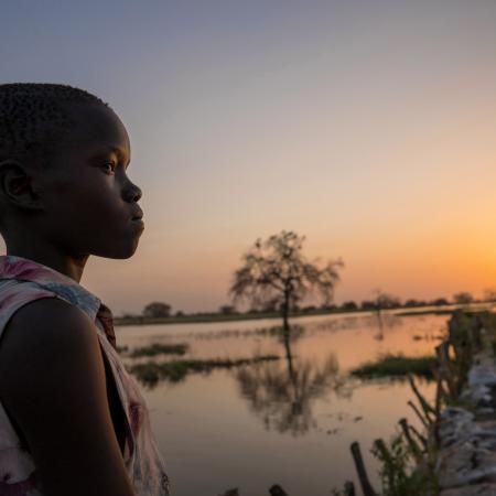 13 year old Ayak Anhiany Lual walks past flooded water outside the village of Panyagor in Twic East, Jonglei State in South Sudan.