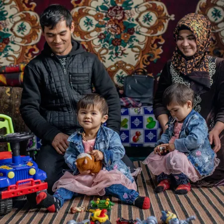 2-year-old twin sisters Fotima (left) and Zuhro pose for a portrait with their parents Namazqul Eshquvatov (left), 27, and Rahima Kushakova, 23, at their home in Burmai Poyon village.