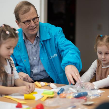 David Morley interacting with children sitting at child's table. 