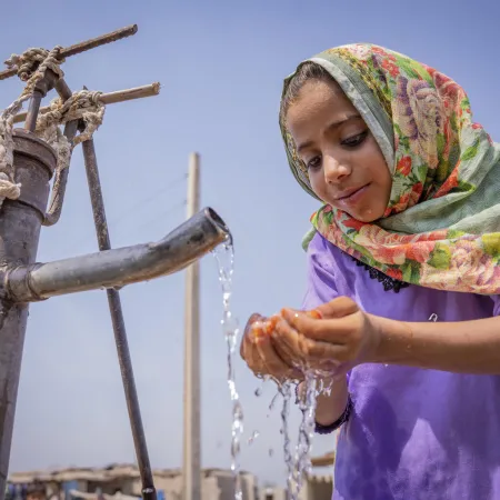 Nafisa (6) drinking water from a community handpump.