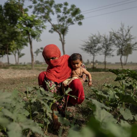 A mother works in the fields with her six-month baby in South Punjab Province.